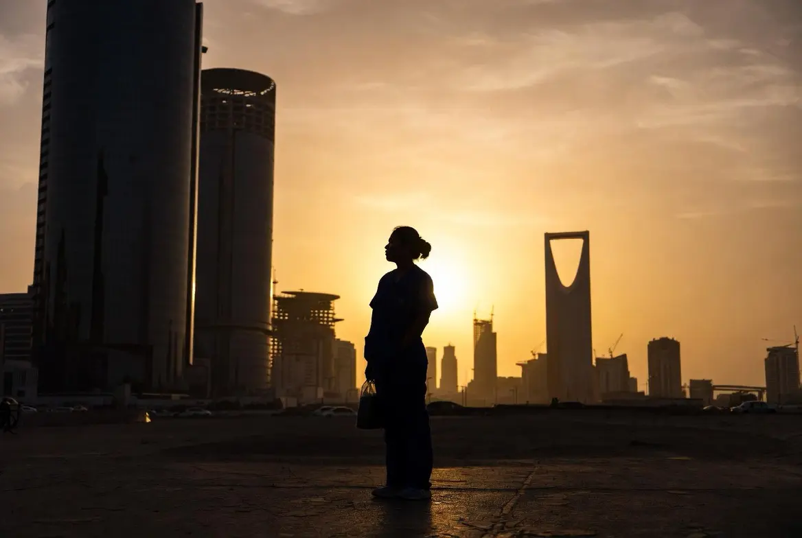 Silhouette of a healthcare worker in scrubs standing against the Riyadh skyline at sunset, with the Kingdom Centre Tower visible in the background — symbolizing the Filipino OFW experience navigating Saudi Arabia's 2025 labor reforms.